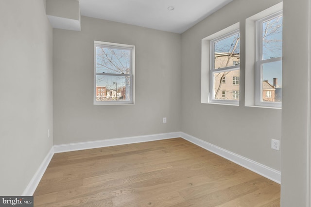 spare room featuring baseboards and wood finished floors