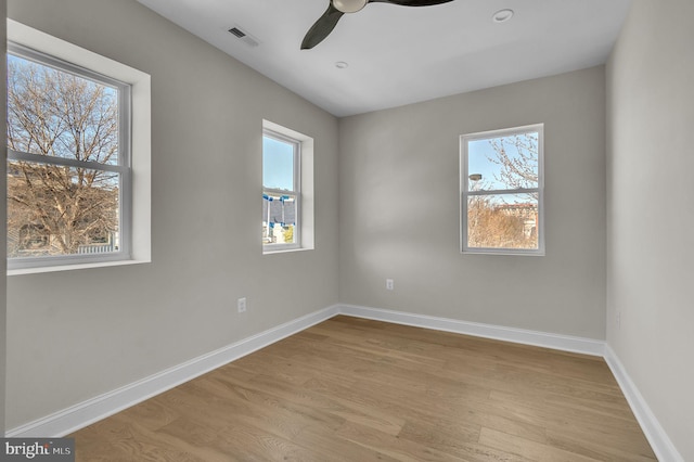 spare room featuring a healthy amount of sunlight, baseboards, and wood finished floors