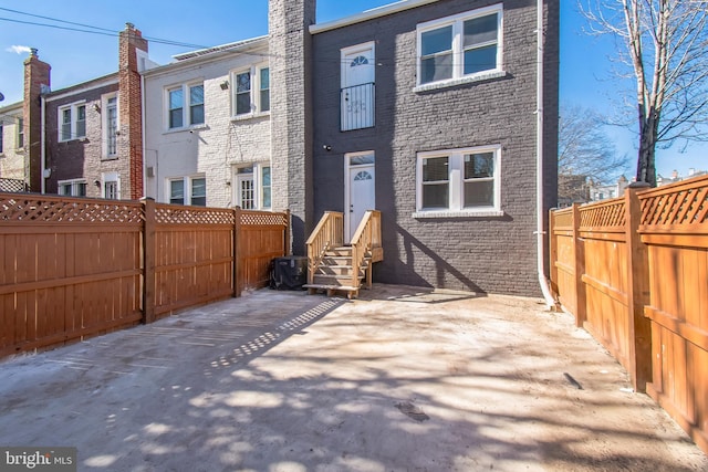 rear view of property with brick siding and fence