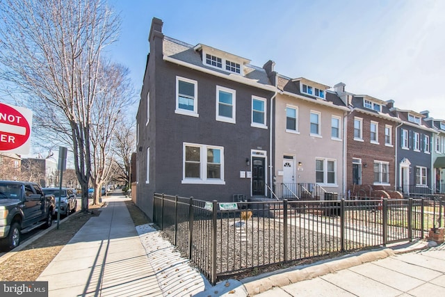 multi unit property with a fenced front yard, a residential view, and brick siding