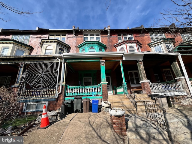 multi unit property featuring covered porch and brick siding