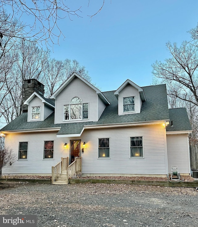 view of front facade with a shingled roof and a chimney