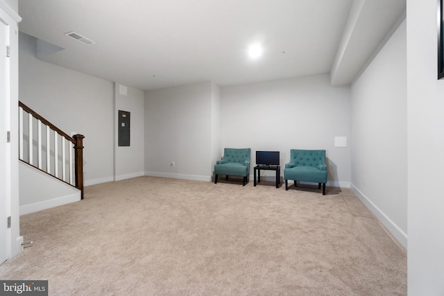 unfurnished room featuring light colored carpet, visible vents, baseboards, stairs, and electric panel