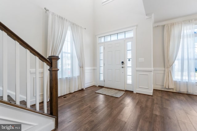 foyer entrance featuring a wainscoted wall, stairway, wood finished floors, and a decorative wall