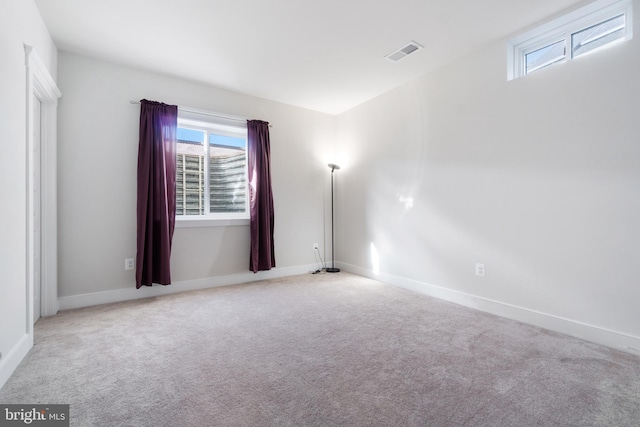 carpeted spare room featuring baseboards and visible vents