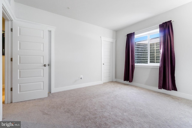 spare room featuring carpet floors and baseboards