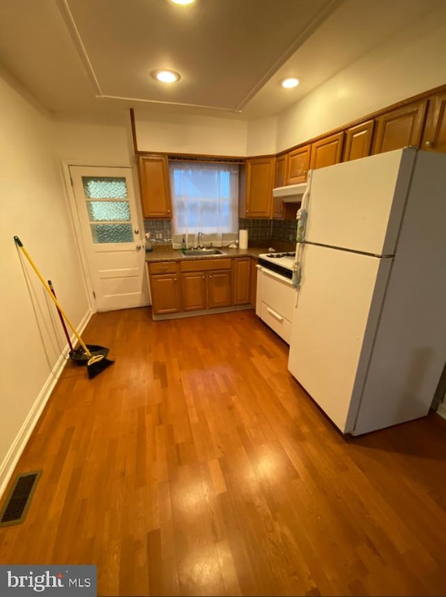 kitchen featuring white appliances, tasteful backsplash, visible vents, dark wood finished floors, and a sink