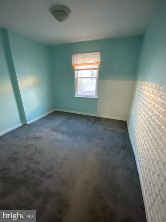 spare room with dark carpet and baseboards