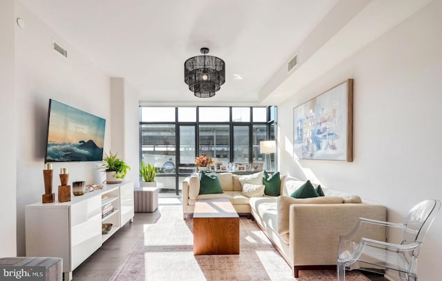 living room featuring floor to ceiling windows, visible vents, and wood finished floors