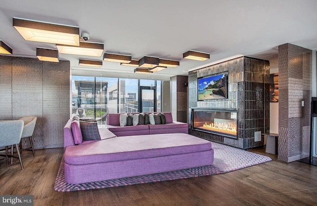 living room featuring wood finished floors, a wall of windows, and a glass covered fireplace