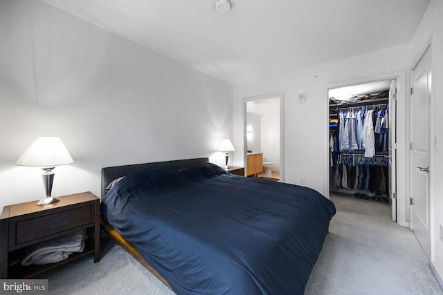 carpeted bedroom with a walk in closet, a closet, and ensuite bath