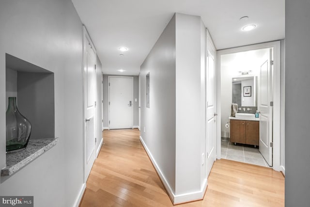 hall with light wood-style flooring and baseboards