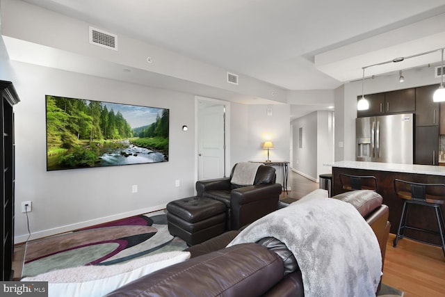 cinema room with track lighting, visible vents, light wood-style flooring, and baseboards