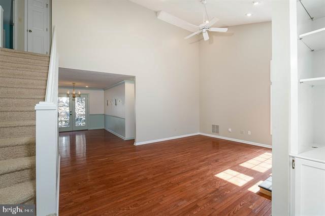 unfurnished living room with french doors, visible vents, stairway, a ceiling fan, and wood finished floors