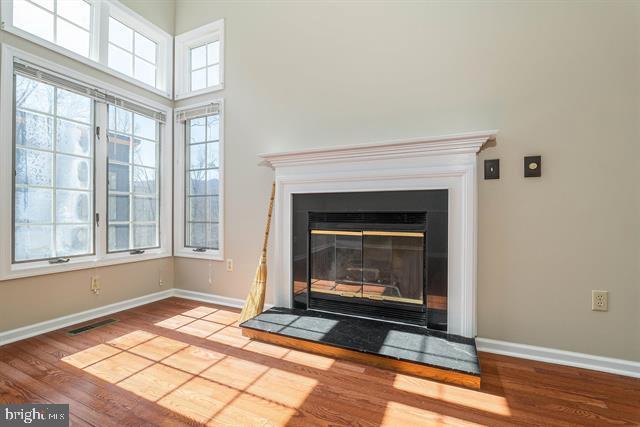 interior details with a glass covered fireplace, visible vents, baseboards, and wood finished floors