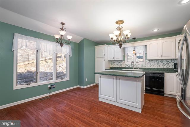 kitchen with a notable chandelier, a sink, white cabinets, dishwasher, and dark countertops