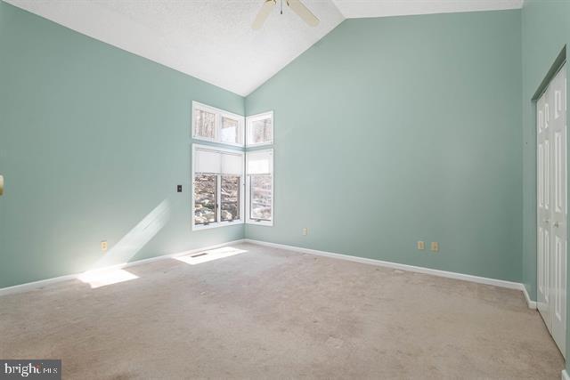 unfurnished bedroom featuring high vaulted ceiling, carpet flooring, a ceiling fan, baseboards, and a closet