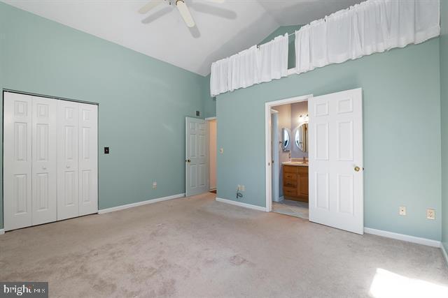 unfurnished bedroom featuring lofted ceiling, baseboards, carpet floors, and a closet