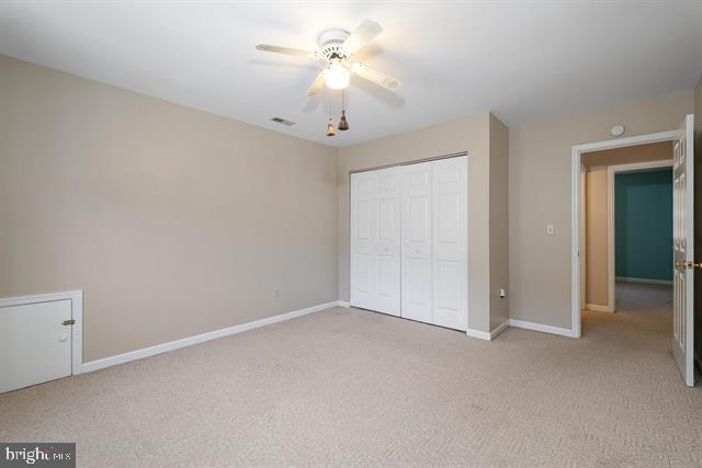 unfurnished bedroom with visible vents, baseboards, a closet, and light colored carpet