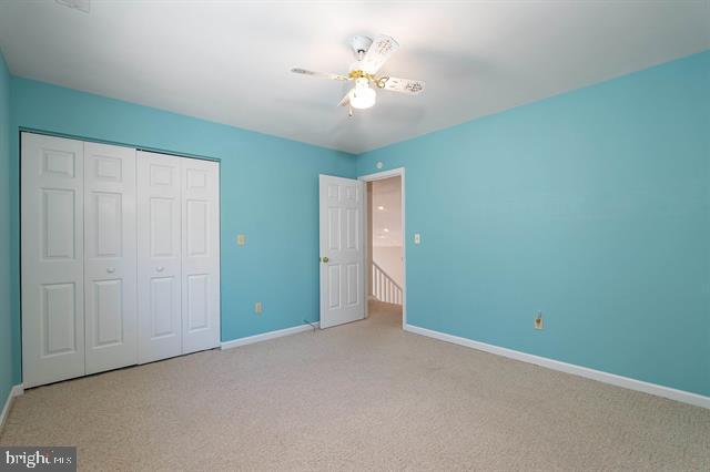 unfurnished bedroom featuring a ceiling fan, baseboards, a closet, and carpet flooring