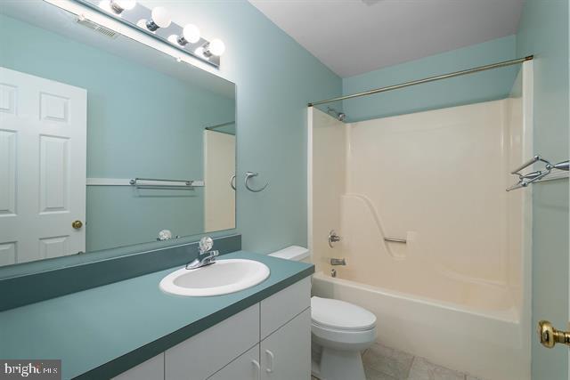 full bath with toilet, shower / bath combination, visible vents, vanity, and tile patterned floors