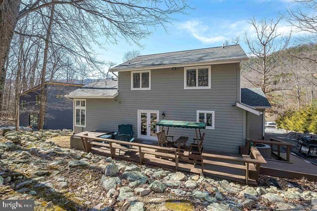 back of property with central AC unit, a deck, and french doors