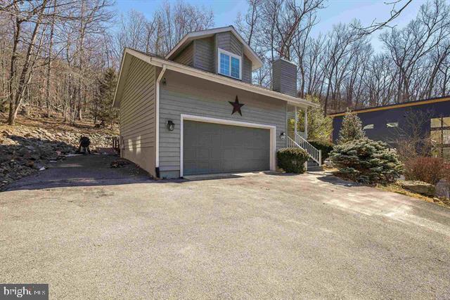 view of side of property featuring a garage, driveway, and a chimney