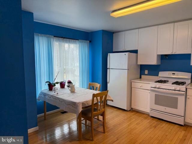 kitchen featuring light countertops, white appliances, light wood-type flooring, and white cabinetry