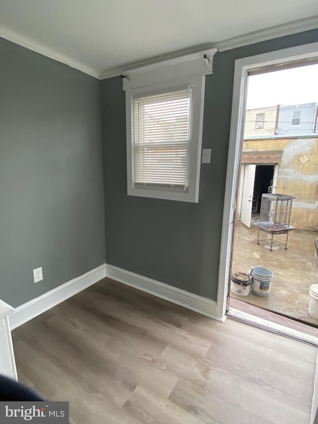 spare room with ornamental molding, wood finished floors, and baseboards