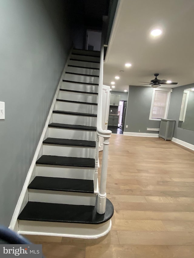 stairway with recessed lighting, ceiling fan, baseboards, and wood finished floors