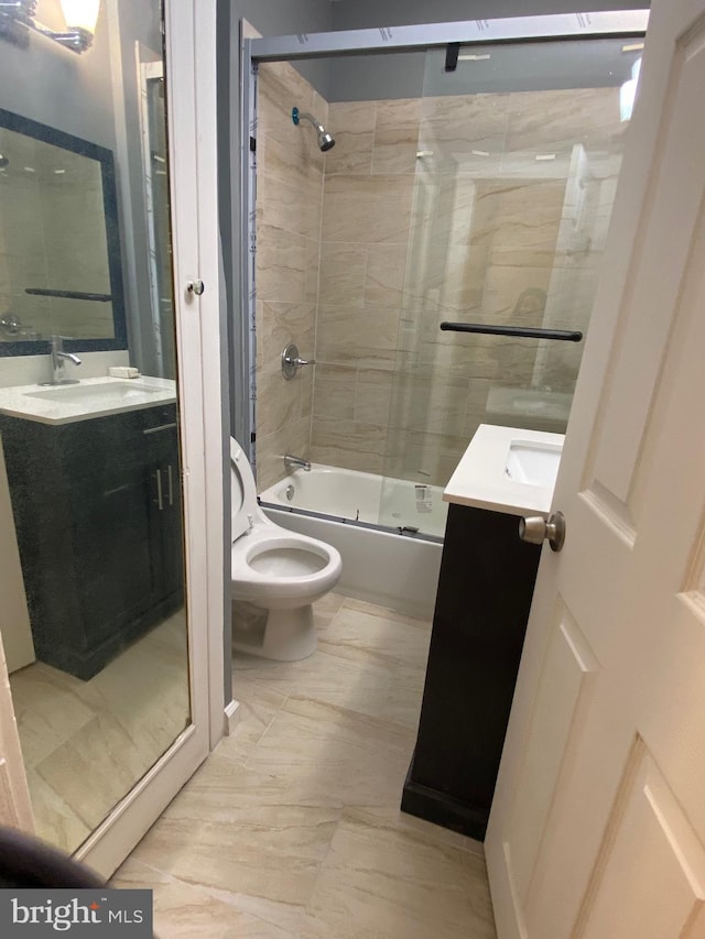 full bath featuring toilet, bath / shower combo with glass door, and vanity