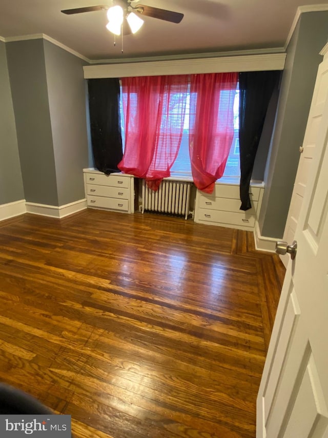 unfurnished bedroom with baseboards, radiator heating unit, ornamental molding, and wood finished floors