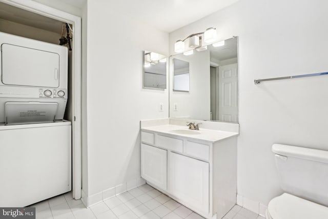 bathroom with stacked washer and clothes dryer, baseboards, vanity, and toilet