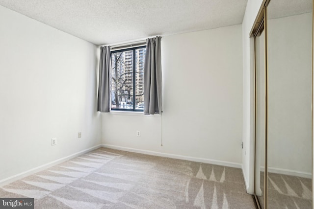 unfurnished bedroom with a closet, carpet flooring, a textured ceiling, and baseboards