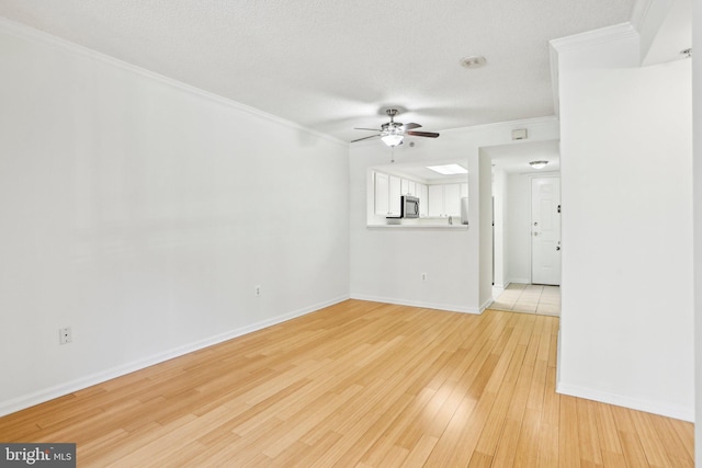 unfurnished living room featuring crown molding, light wood finished floors, ceiling fan, a textured ceiling, and baseboards