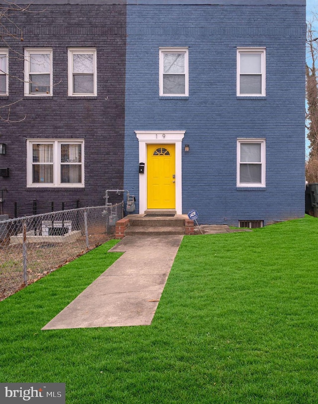 view of front of house with a front yard, brick siding, and fence