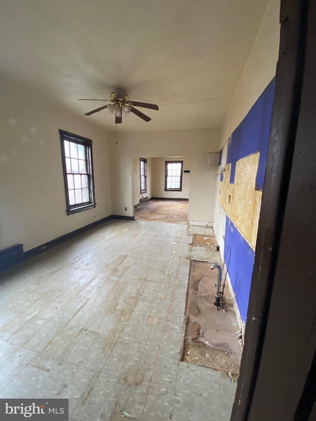 unfurnished living room featuring baseboards and a ceiling fan