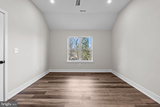 empty room featuring lofted ceiling, visible vents, baseboards, and wood finished floors