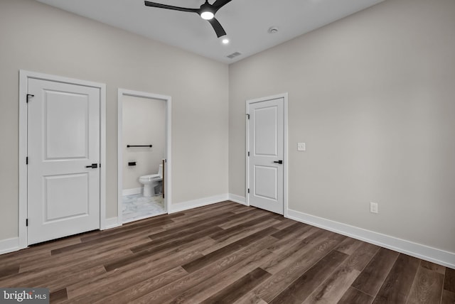 unfurnished bedroom with ensuite bathroom, dark wood finished floors, visible vents, and baseboards