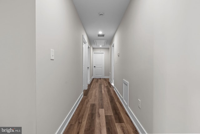 hallway featuring attic access, dark wood-style flooring, visible vents, and baseboards