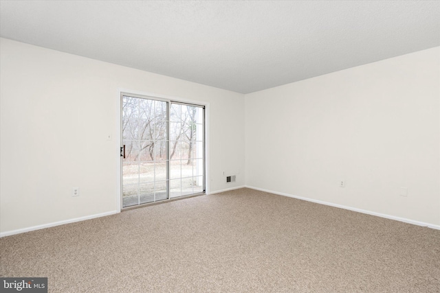 spare room featuring carpet floors, visible vents, and baseboards