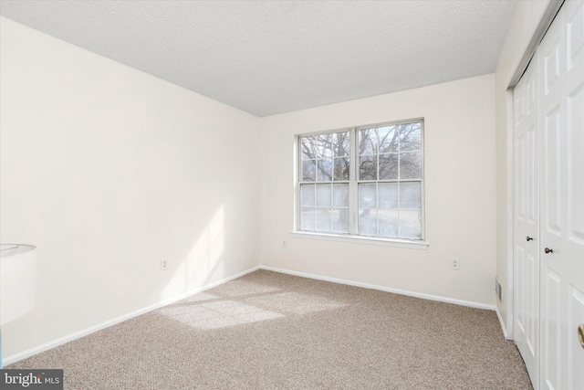 unfurnished bedroom with a textured ceiling, a closet, carpet, and baseboards