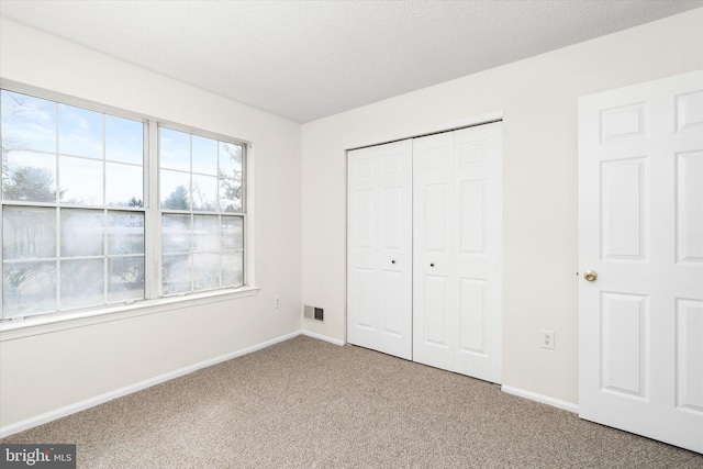 unfurnished bedroom featuring carpet, a closet, visible vents, and baseboards