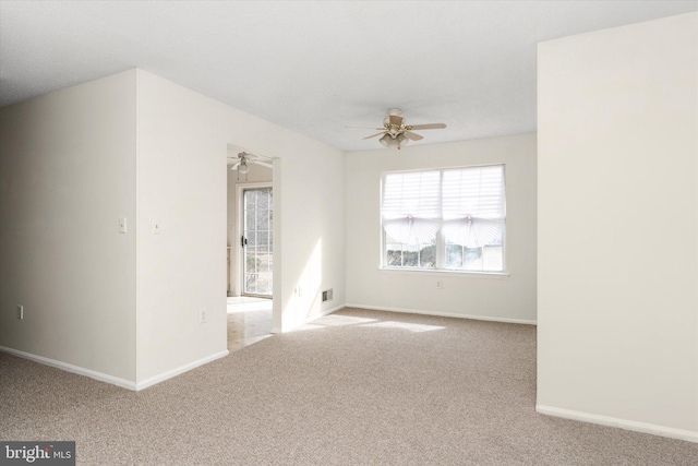 carpeted spare room featuring ceiling fan, visible vents, and baseboards