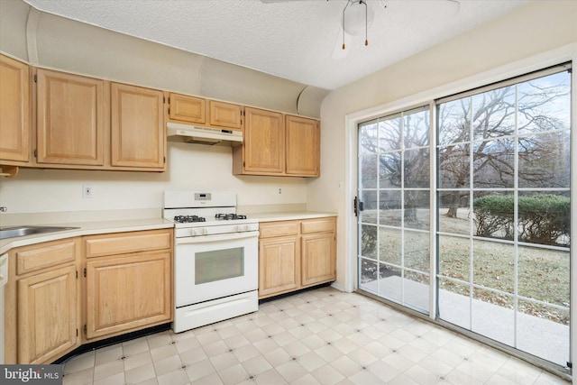 kitchen featuring under cabinet range hood, white range with gas stovetop, light countertops, and light floors