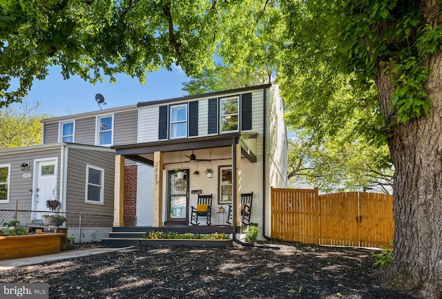 view of front of home with a porch, brick siding, and fence