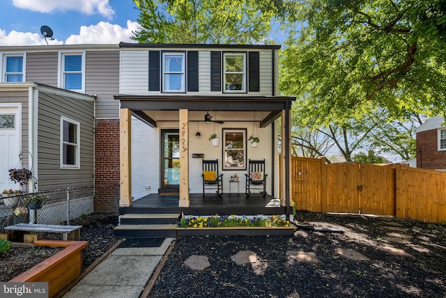 view of front of property with a porch, a vegetable garden, fence, and brick siding