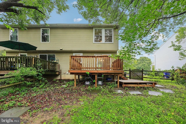 rear view of house featuring a wooden deck and fence