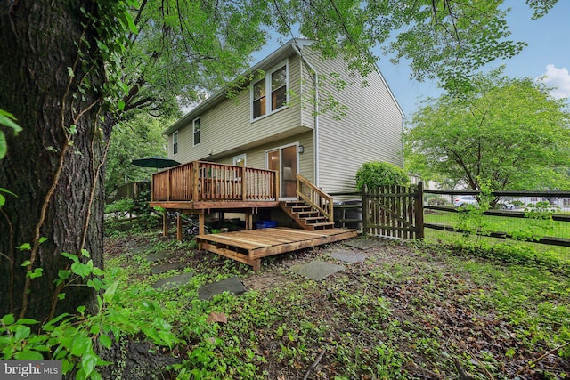 back of property featuring a deck, fence, and a gate