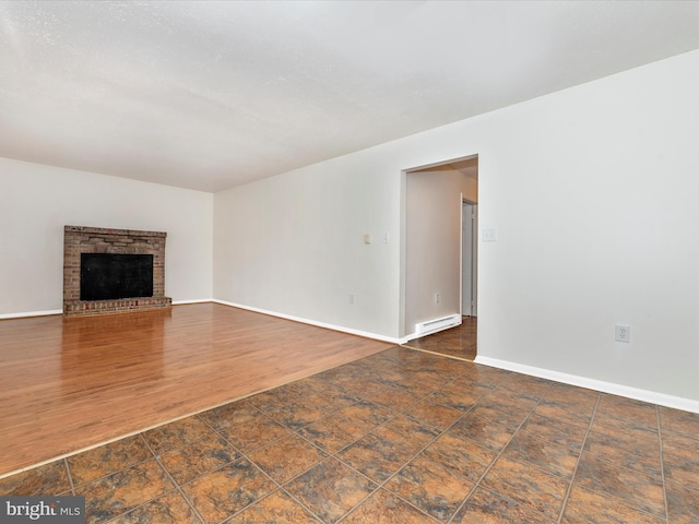 unfurnished living room with a baseboard radiator, a fireplace, baseboards, and wood finished floors